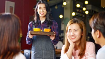 Một phụ nữ đứng cạnh người học đang ngồi tại bàn